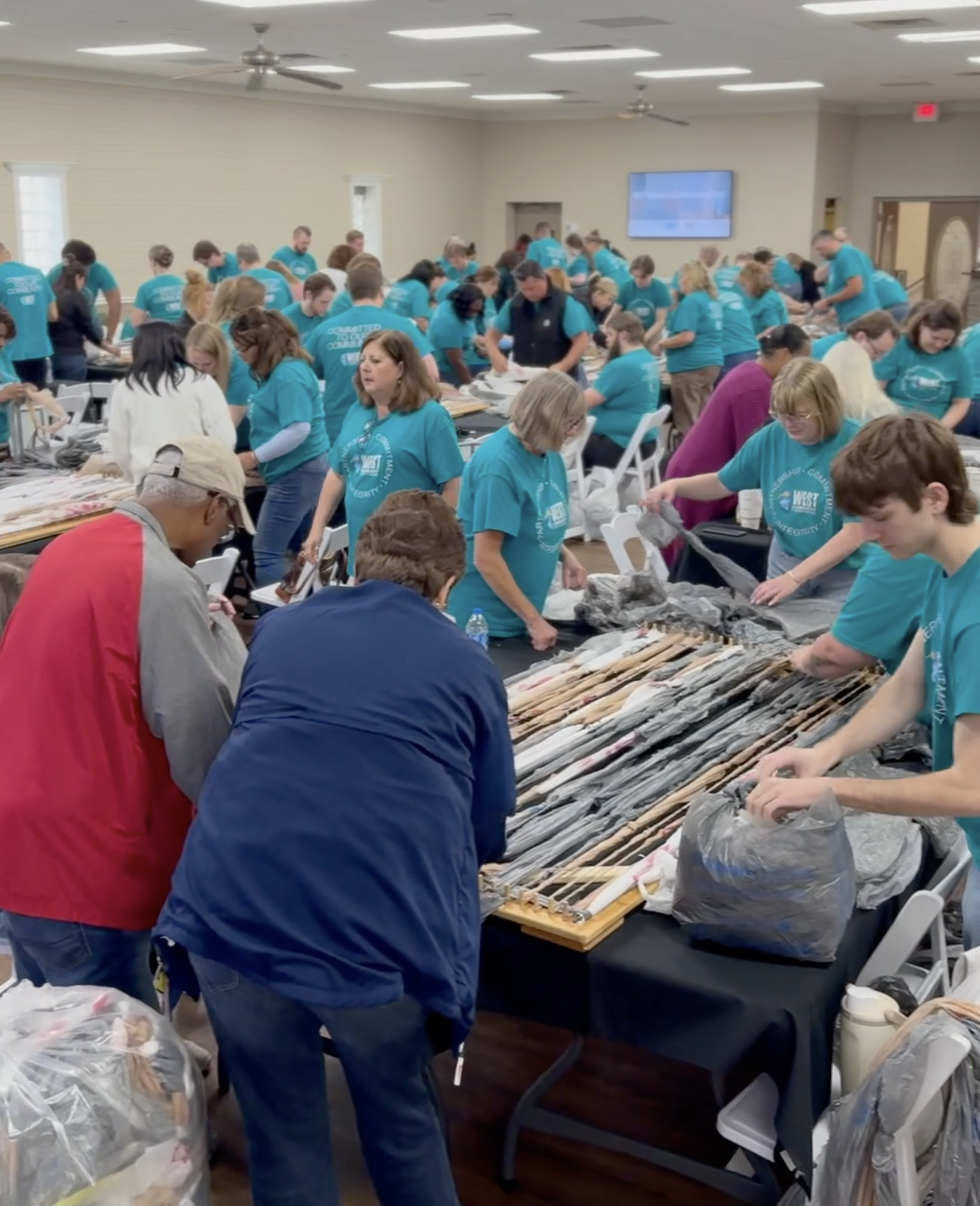 Photo of our staff weaving sleep mats for the unhoused out of recycled plastic bags at our CU Make a Difference day.